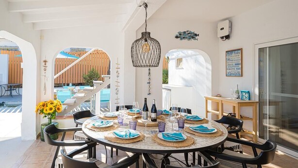 A round dining table set with plates, cutlery, and glasses, surrounded by black chairs. - House in quiet and green surrounding where you can disconnect and enjoy family (La Nucia)