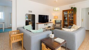 A living room with two grey sofas, a wooden chair, a TV, a lamp, and a cabinet with glass doors. - House in quiet and green surrounding where you can disconnect and enjoy family (La Nucia)