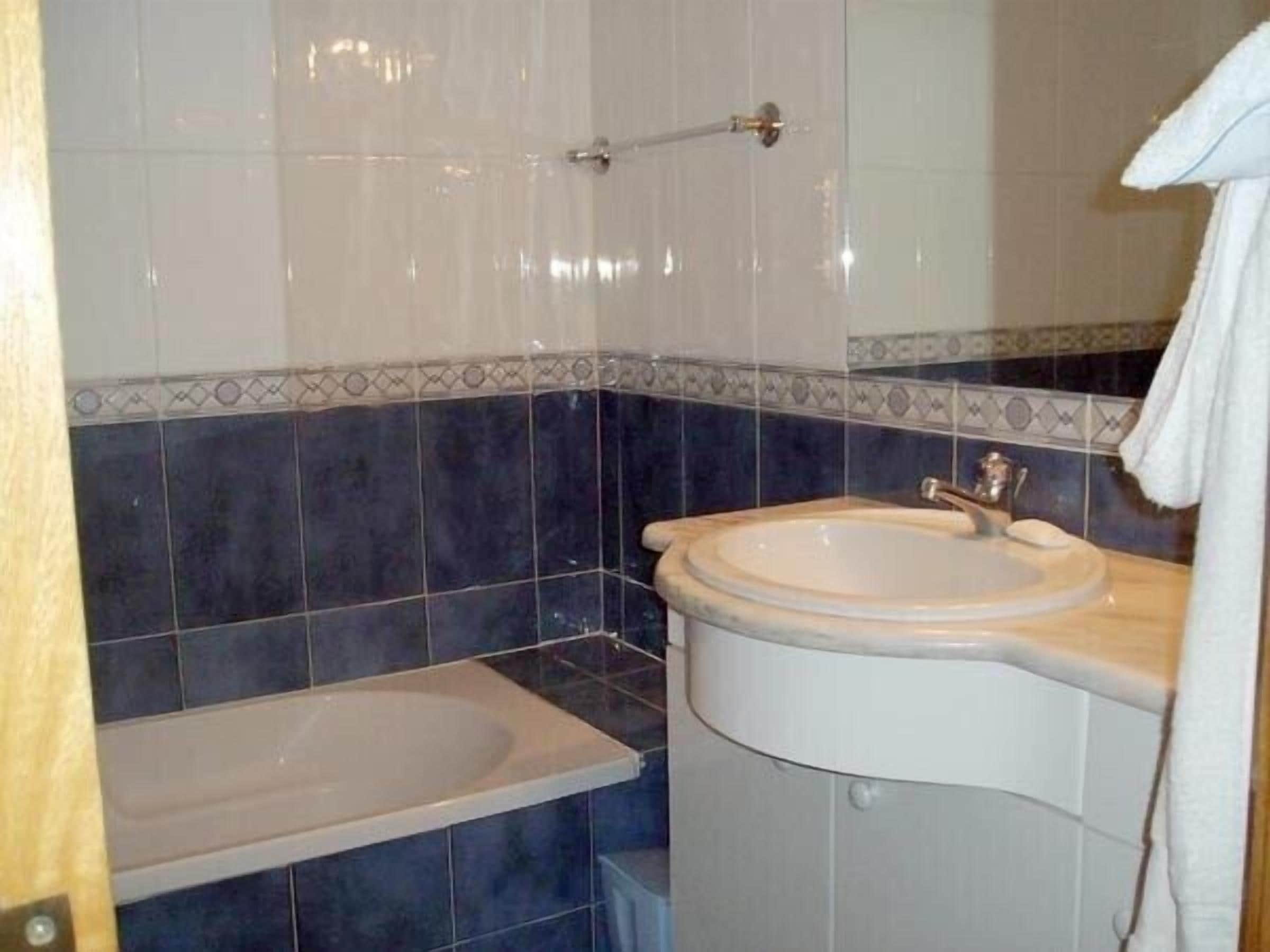 Un baño con lavamanos, espejo y bañera.