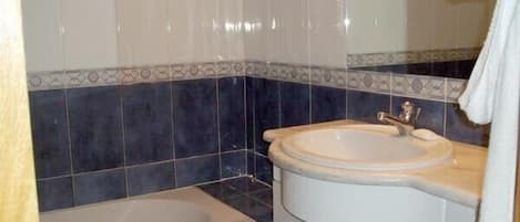 Un baño con lavamanos, espejo y bañera.