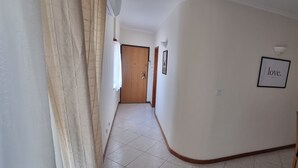 Un passadís amb una porta de fusta, un quadre al mur i una taula amb una cadira.