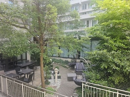 Ein Innenhof mit Sitzgelegenheiten im Freien, einem Baum und einem Gebäude im Hintergrund.