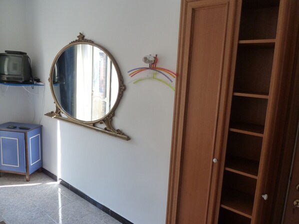 Une pièce avec une armoire en bois, une commode bleue et un miroir au mur.