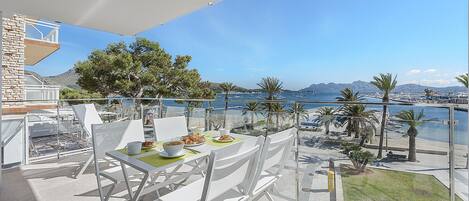 A balcony with a table set for breakfast, overlooking a marina with boats and a clear sky.