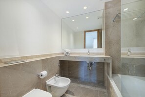 Une salle de bain moderne équipée d’un bidet, de toilettes et d’une douche à parois de verre.