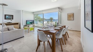 Ein modernes Wohnzimmer mit Essbereich, großen Fenstern und einem Fernseher.