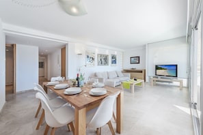 Una sala de estar moderna con comedor, un sofá, un televisor y obras de arte en las paredes.