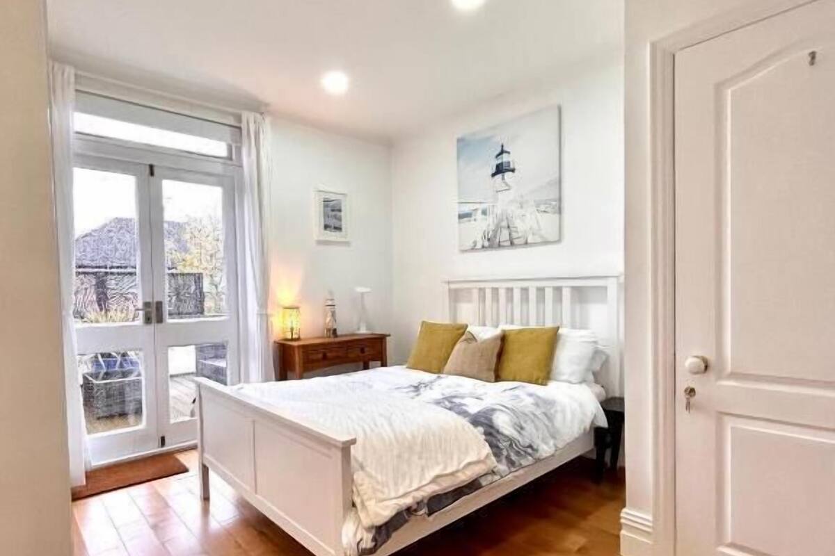 A bedroom with a bed, a nightstand, a lamp, and a door.