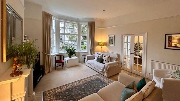 A spacious living room with a large window, a sofa set, a coffee table, and a fireplace. - Holland House (Wallasey)