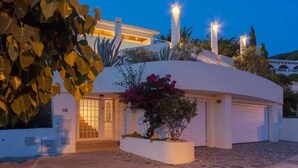 A modern building with a curved roof, a gated entrance, and a well-maintained garden with flowering plants. - VILLA LANTANA - Class and style with incredible views over Mahon harbour (Mao)