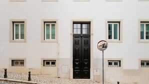 A building with a black double door, multiple windows, and a cobblestone street.