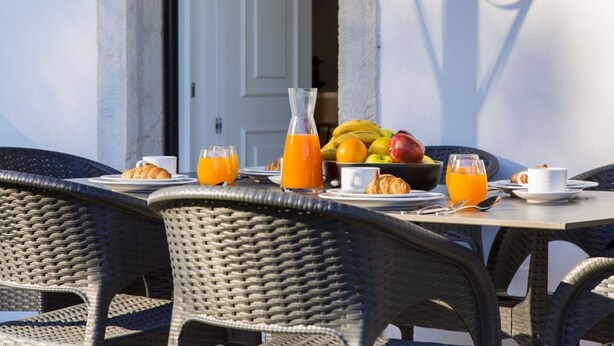 A breakfast table with plates, croissants, and a fruit bowl.