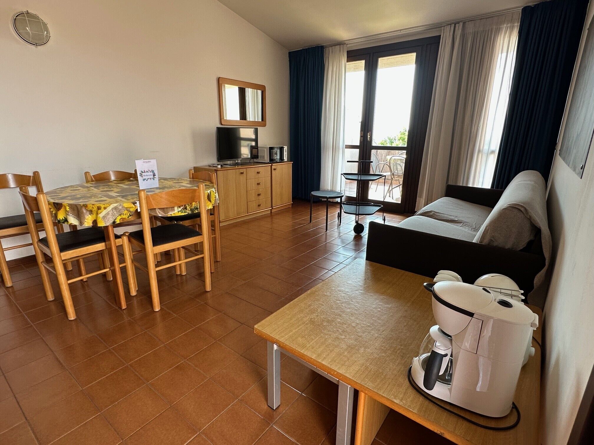 Ein kleines Hotelzimmer mit Essbereich, Küchenzeile und einem Bett.