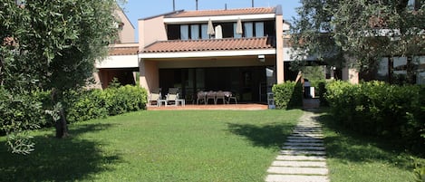 A two-story house with a covered patio and a stone pathway leading to the entrance.
