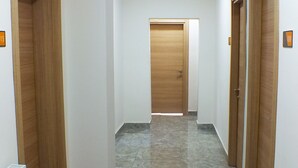 A hallway with marble flooring, wooden doors, and white walls. - Ankara Otel Evren (Ankara)