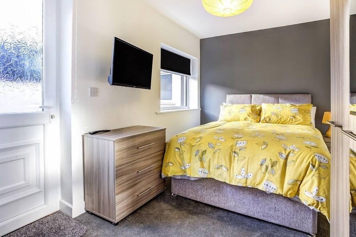 Une chambre à coucher avec un lit, une commode, un téléviseur et une fenêtre.