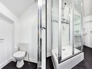 Un baño moderno con ducha de mampara de vidrio, inodoro blanco y lavamanos.