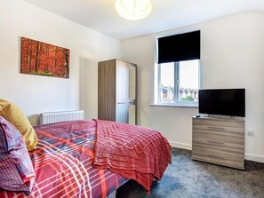 Un dormitorio con cama, cómoda, radiador, ventana y un cuadro en la pared.