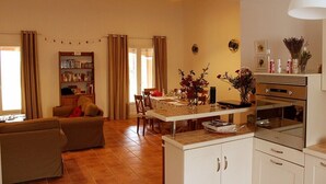 A living room with a sofa, a dining table, and a kitchen area with cabinets and a stove.