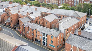 A multi-story brick building with a central courtyard, surrounded by other buildings. - The Loft-Stylish Stay – Sleeps 6 (Southport)