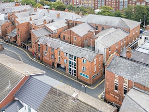 Un immeuble de plusieurs étages, construit en briques, avec une cour intérieure, entouré d’autres bâtiments.