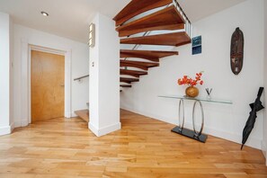 A modern interior with a wooden staircase, a glass console table, and a wooden door.