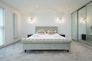 A modern bedroom with a large bed, two bedside tables, and a sliding glass door.