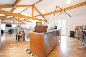 A spacious kitchen with wooden beams, a central island, and a dining area with chairs.