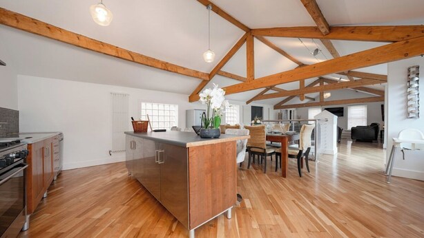 A spacious kitchen with wooden beams, a central island, and a dining area with chairs. - The Loft-Stylish Stay – Sleeps 6 (Southport)