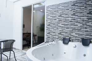 A modern bathroom with a large bathtub, a glass shower enclosure, and a tiled wall.