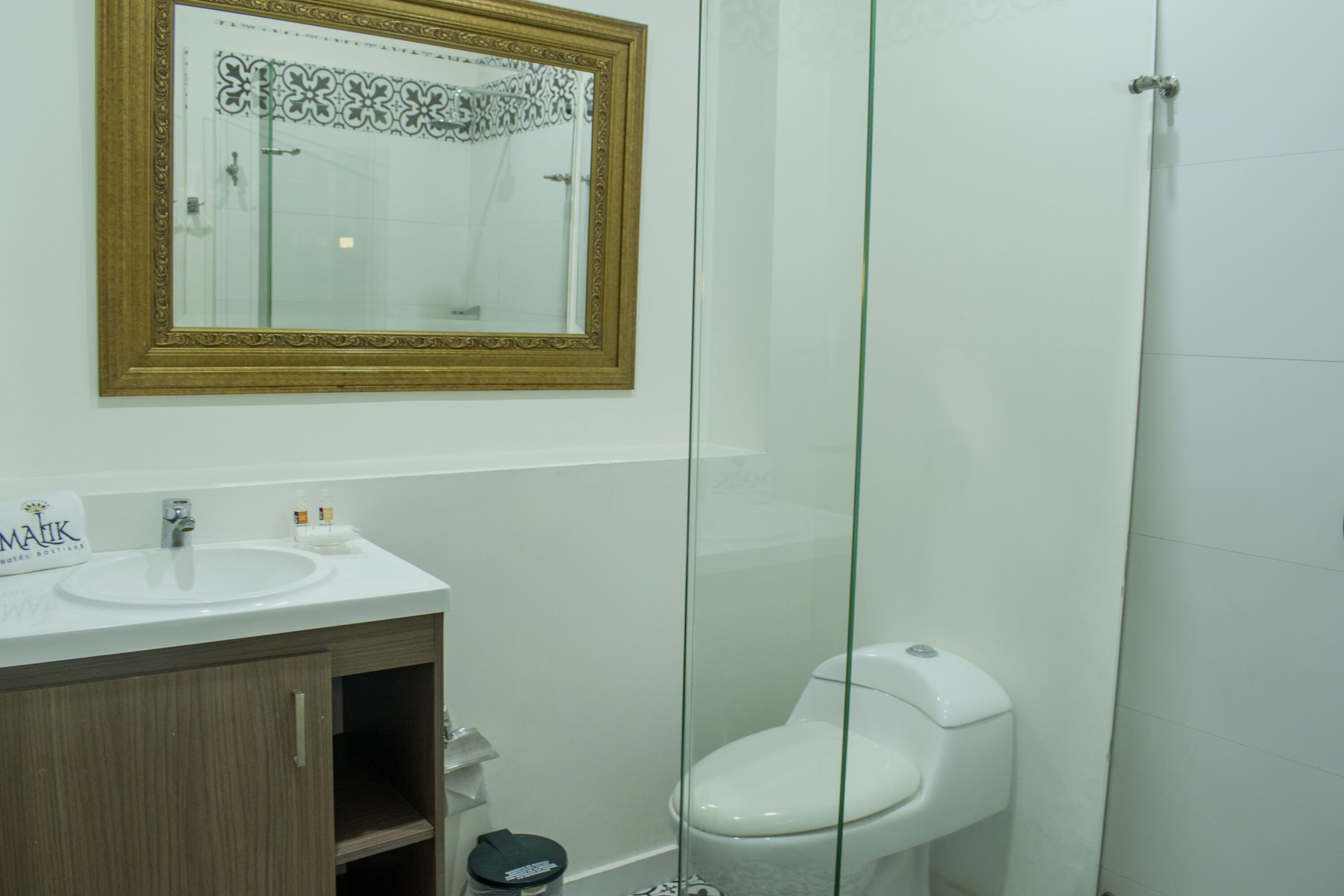 A bathroom with a white sink, mirror, and toilet.