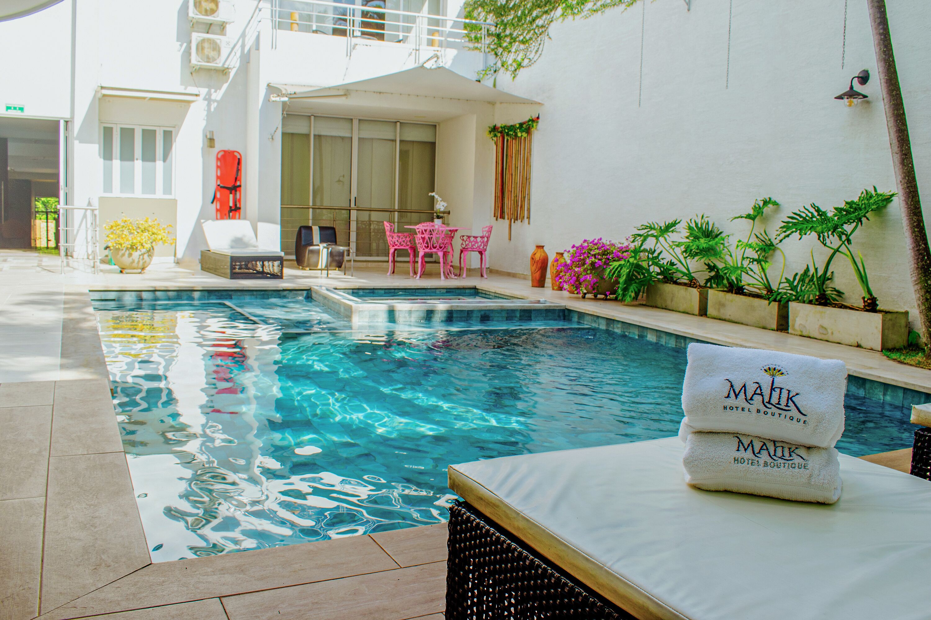 Ein Pool mit Liegestühlen, einem Tisch und Topfpflanzen.