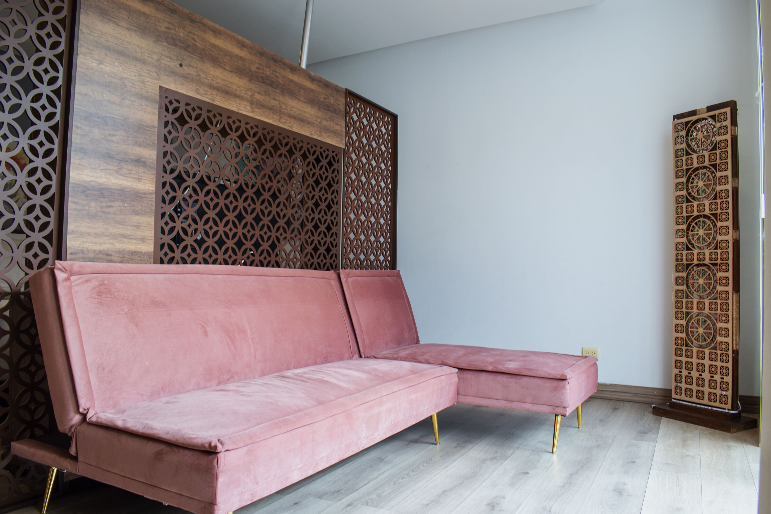 Ein rosafarzenes Ecksofa in einem Raum mit einer Holzvertäfelung und einer dekorativen Wand.