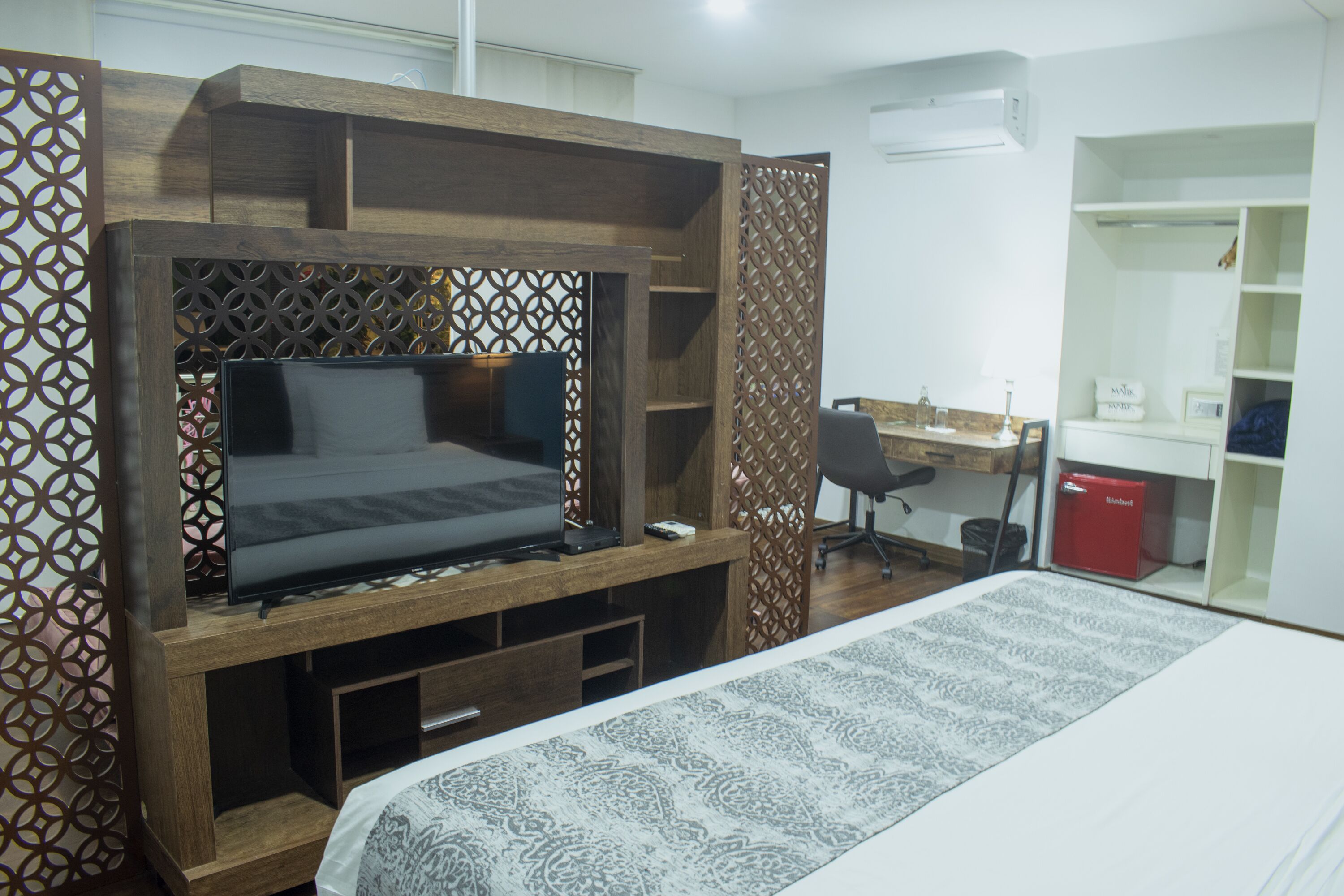 A bedroom with a bed, TV, desk, and wardrobe.