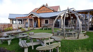 A rustic outdoor seating area with picnic tables and a wooden pergola.