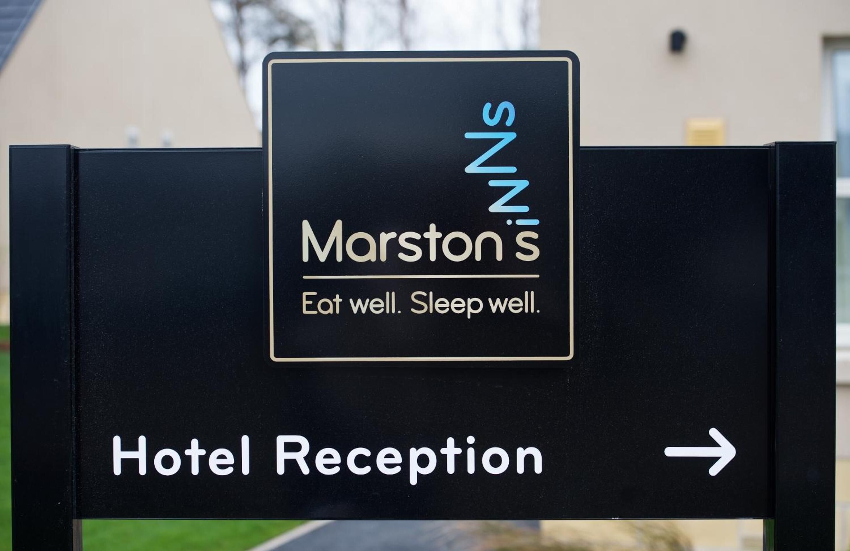 A hotel reception sign with the name 'Marston's' and the slogan 'Eat well. Sleep well.'