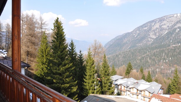 Bergblick mit einem Holzbalkon über einem Dorf mit traditionellen Häusern.