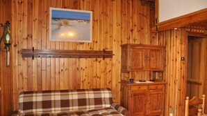 Ein Holzinnenraum mit einem Karo-Sofa, Holzschränken und einem gerahmten Bild an der Wand.