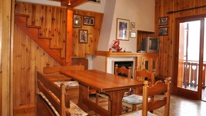 Ein Holzinterieur mit Esstisch, Stühlen, Kamin und Fernseher.