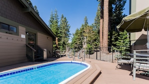 A swimming pool with a tiled edge, a 'NO DOGS' sign, and outdoor seating with a table and chairs. - Crestview #12 Bldg. C (Mammoth Lakes)