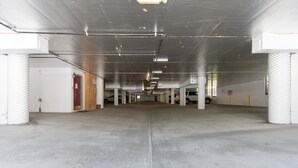 A spacious parking garage with concrete floors and white pillars, featuring multiple parking spaces and a central walkway. - Crestview #12 Bldg. C (Mammoth Lakes)