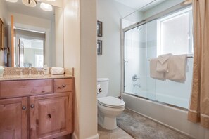 A bathroom with a wooden vanity, a toilet, and a glass-enclosed shower. - Mammoth Gateway Village # 8 (Mammoth Lakes)