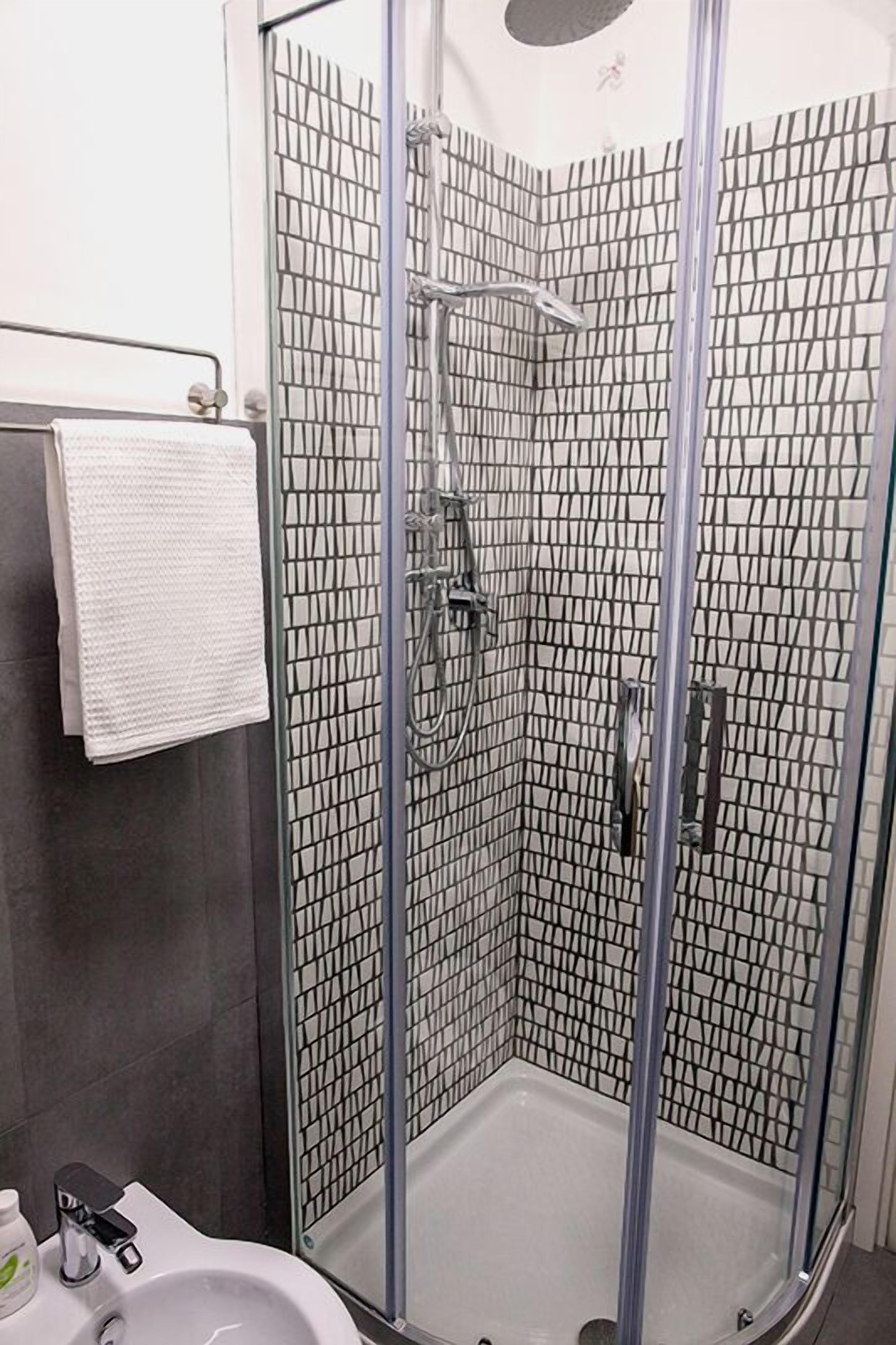 A modern shower enclosure with a glass door and a tiled interior.