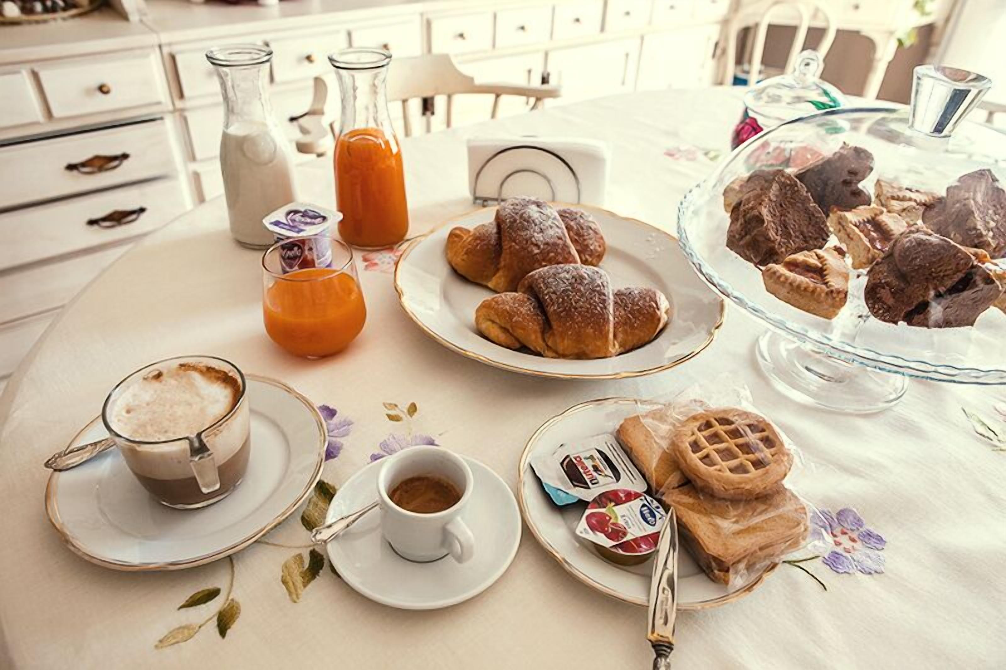 Un desayuno con cruasanes, gofres y bebidas sobre una mesa.