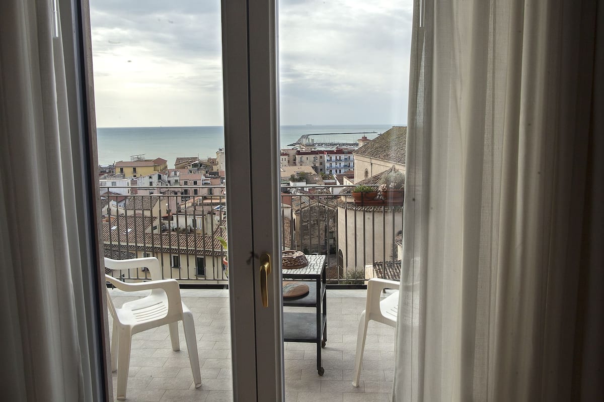 A balcony with a view of the sea and buildings.