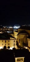 A nighttime view of a cityscape with illuminated buildings and a bridge in the distance.