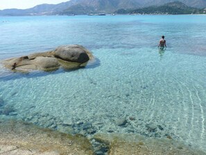 A clear coastal area with a large rock formation in the foreground and a person standing in the water. - VILLASIMIUS Holiday home Sea Wi-Fi Free (Villasimius)