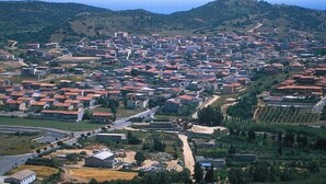 Vue aérienne d’une ville avec un ensemble dense de bâtiments, de routes et de collines verdoyantes en arrière-plan.