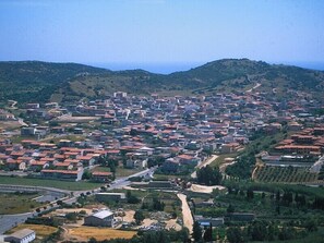 Vista aèria d'una localitat amb un dens conjunt d'edificis, carreteres i turons verds al fons.
