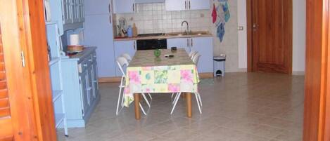 Una cocina compacta con una mesa de comedor, armarios y piso de baldosas.